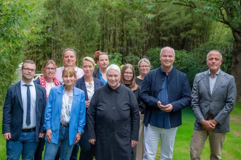 Team von COATRAIN® Hamburg bei einem Gruppenfoto im Garten – Coaches und Mitarbeitende für Coaching, Ausbildung und Training.